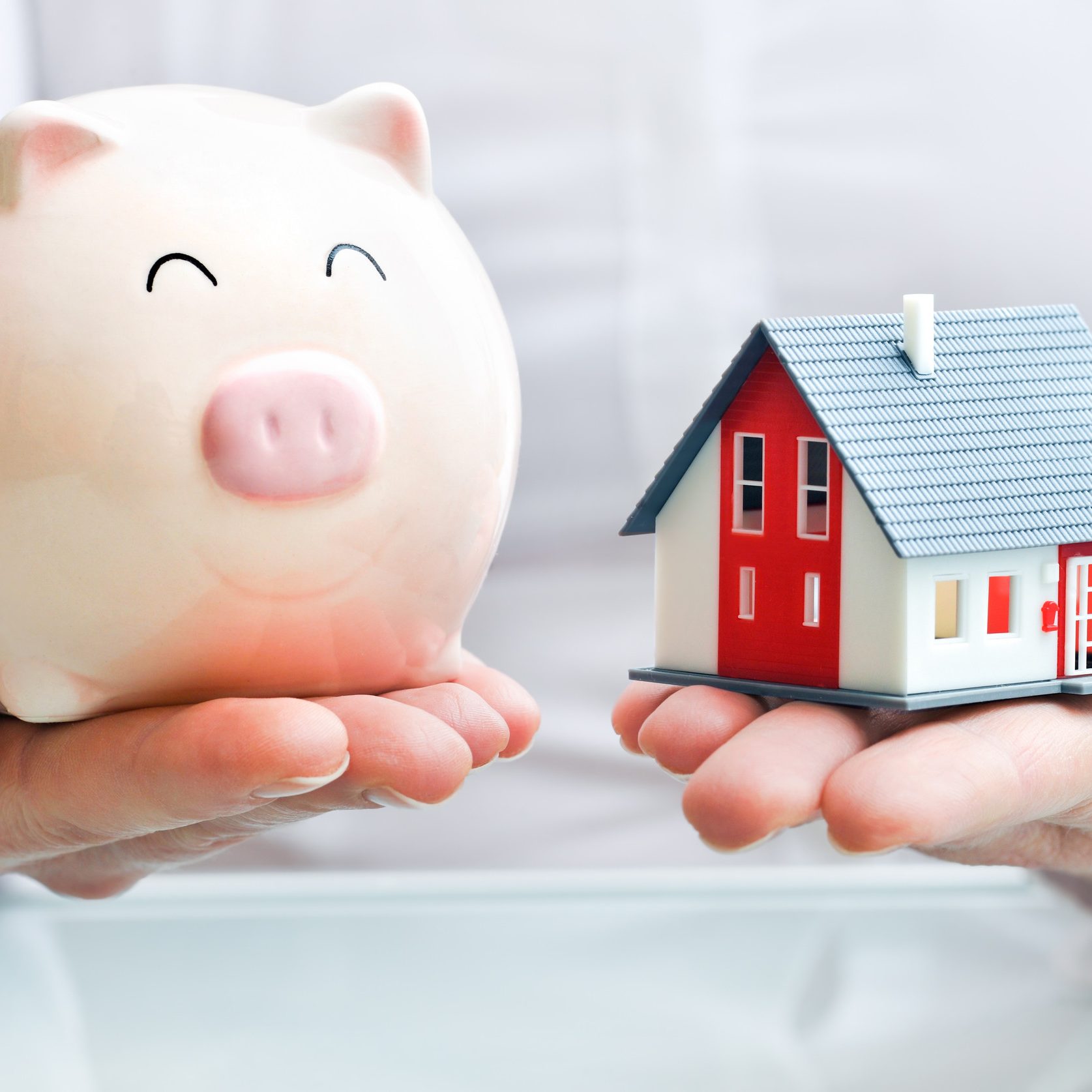 Hands holding a  piggy bank and a house model  Housing industry mortgage plan and residential tax saving strategy